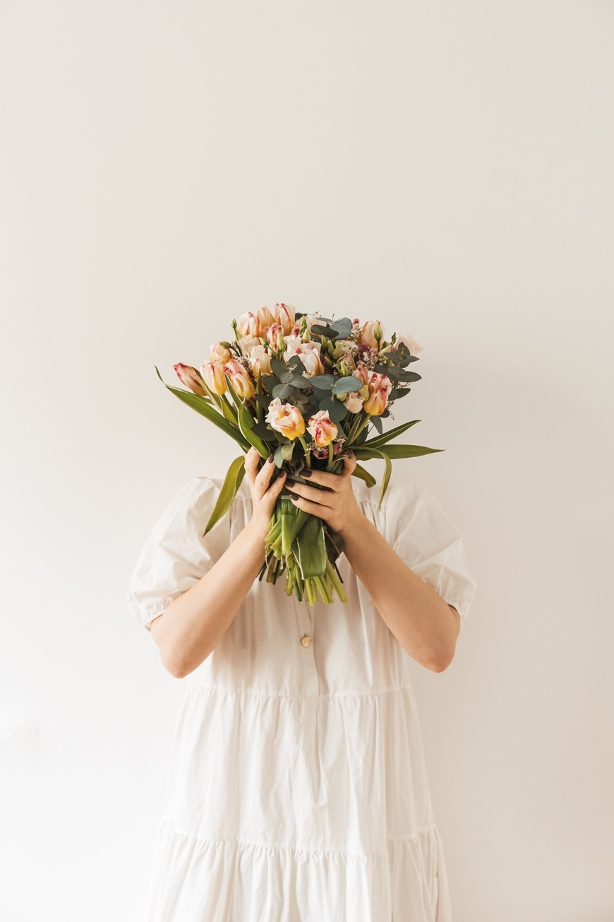 Woman in White Dress Holding Bouquet of Flowers